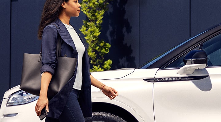 A woman approaches a 2024 Lincoln Corsair® SUV while holding a smartphone. | Lincoln Demo 5 in Derwood MD